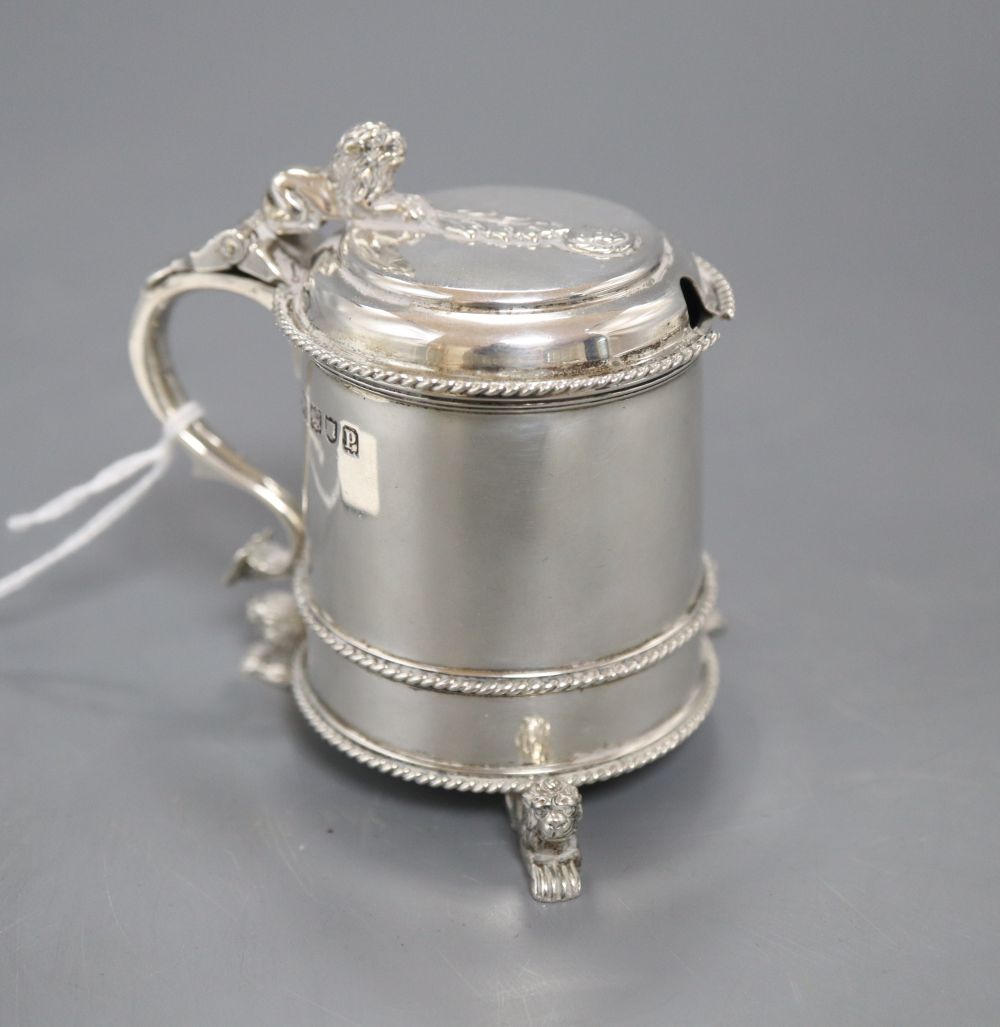 A George V silver mustard pot with blue glass liner, on three recumbent lion feet, Mappin & Webb, London, 1910, 79mm.